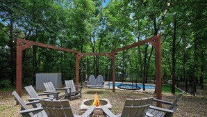 Ein Außenbereich mit Adirondack-Stühlen, einer Feuerstelle und einer Schaukel.