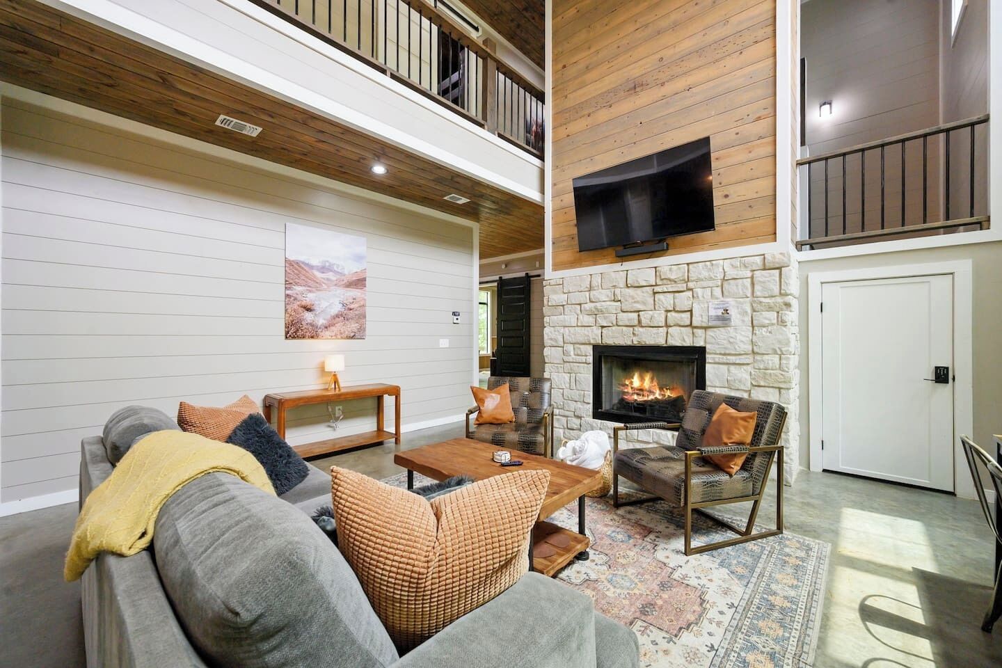 A living room with a fireplace, a sofa set, a coffee table, and a television mounted on the wall.