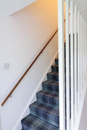 A staircase with a wooden handrail and a white wall.