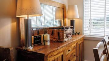 A wooden dresser with a mirror, two lamps, wicker baskets, and a sign.