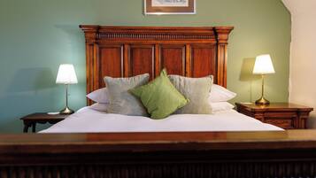 A neatly made bed with a wooden headboard, two bedside lamps, and a framed picture on the wall.