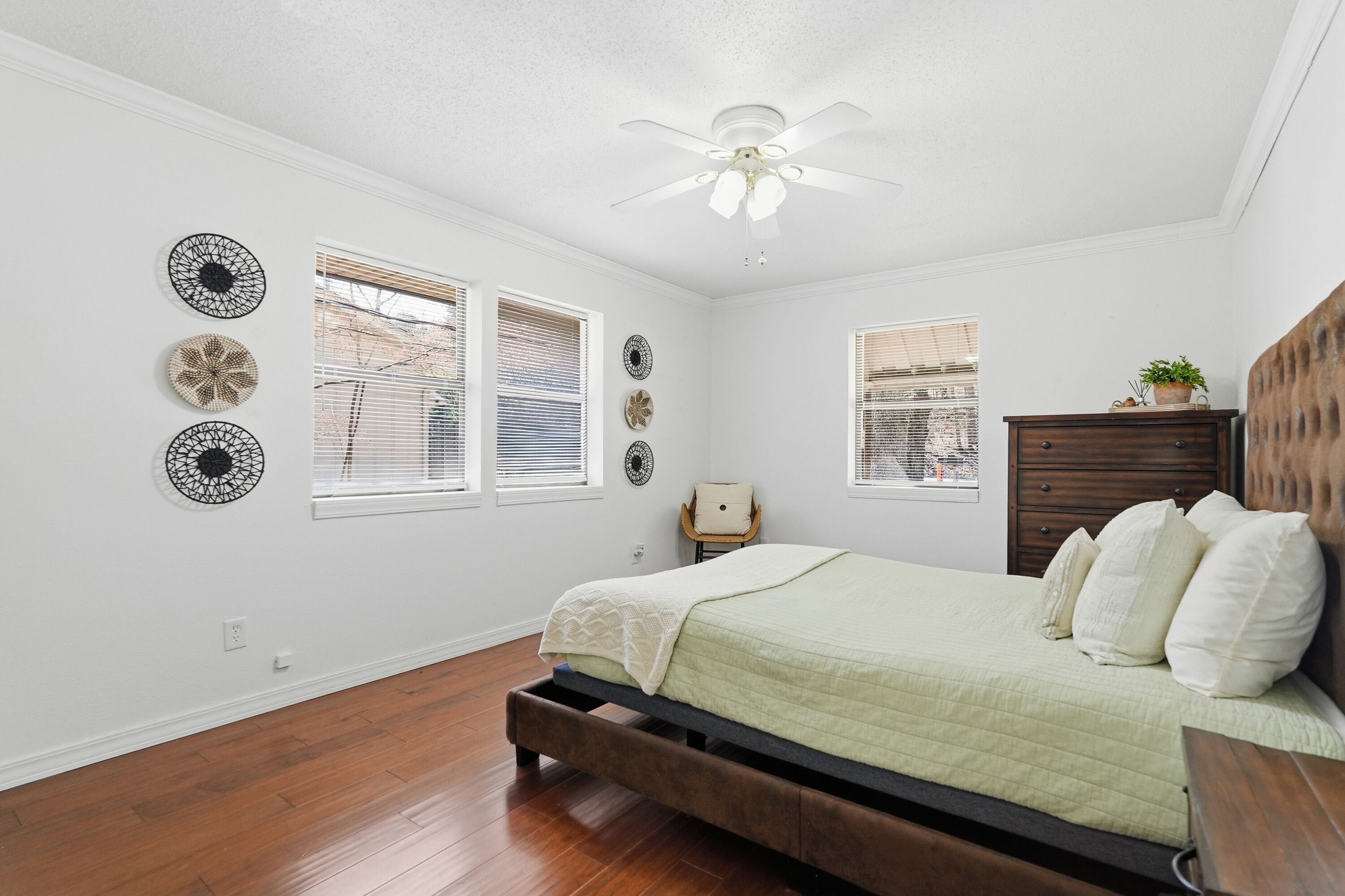 A bedroom with a bed, a ceiling fan, and decorative wall art.