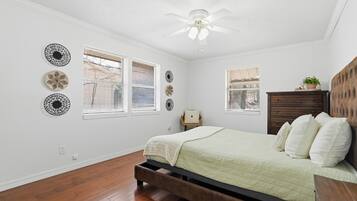 A bedroom with a bed, a ceiling fan, and decorative wall art.