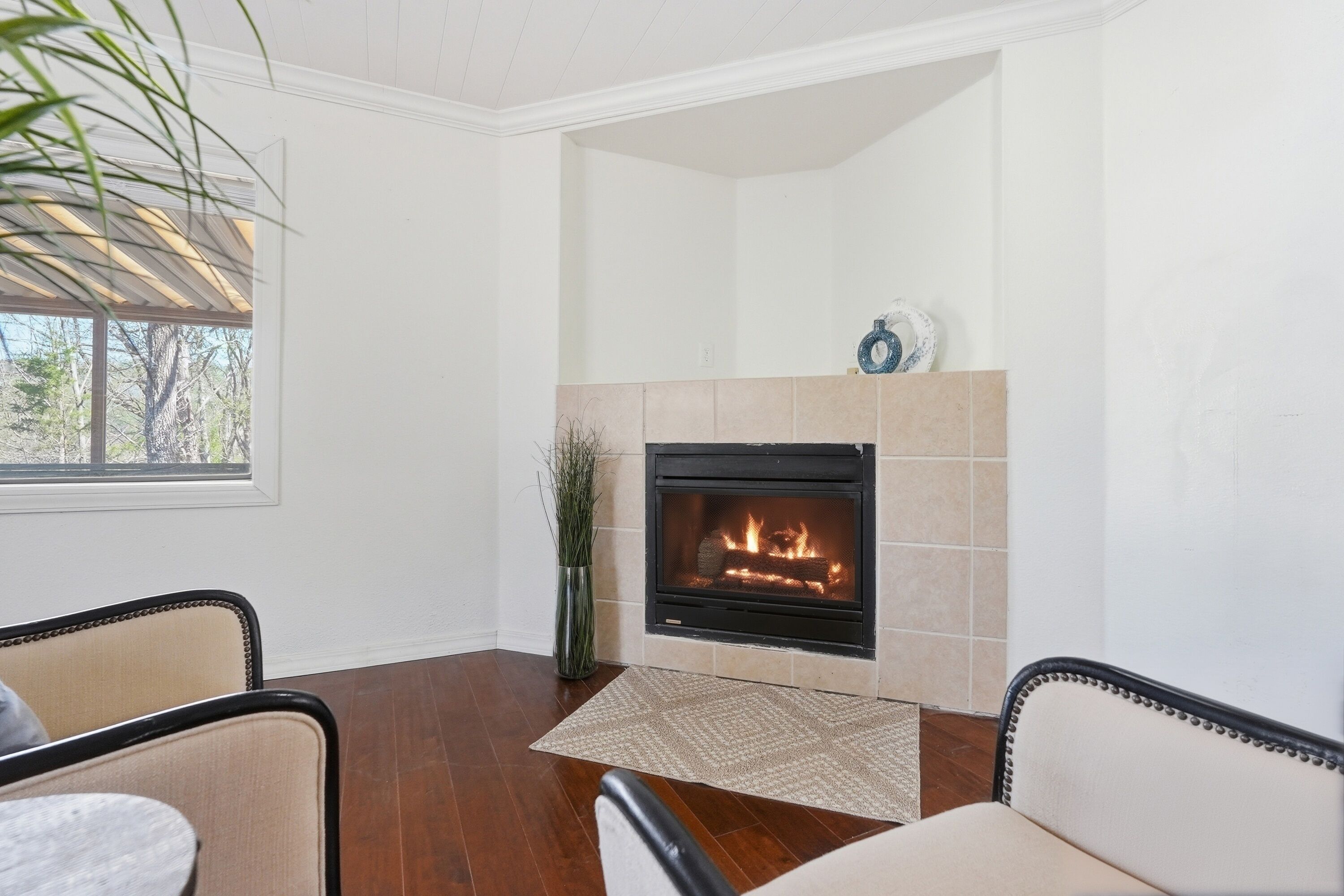 Une pièce avec une cheminée, un plancher en bois et deux fauteuils.