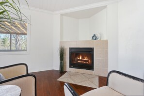 Ein Zimmer mit Kamin, Holzboden und zwei Sesseln.