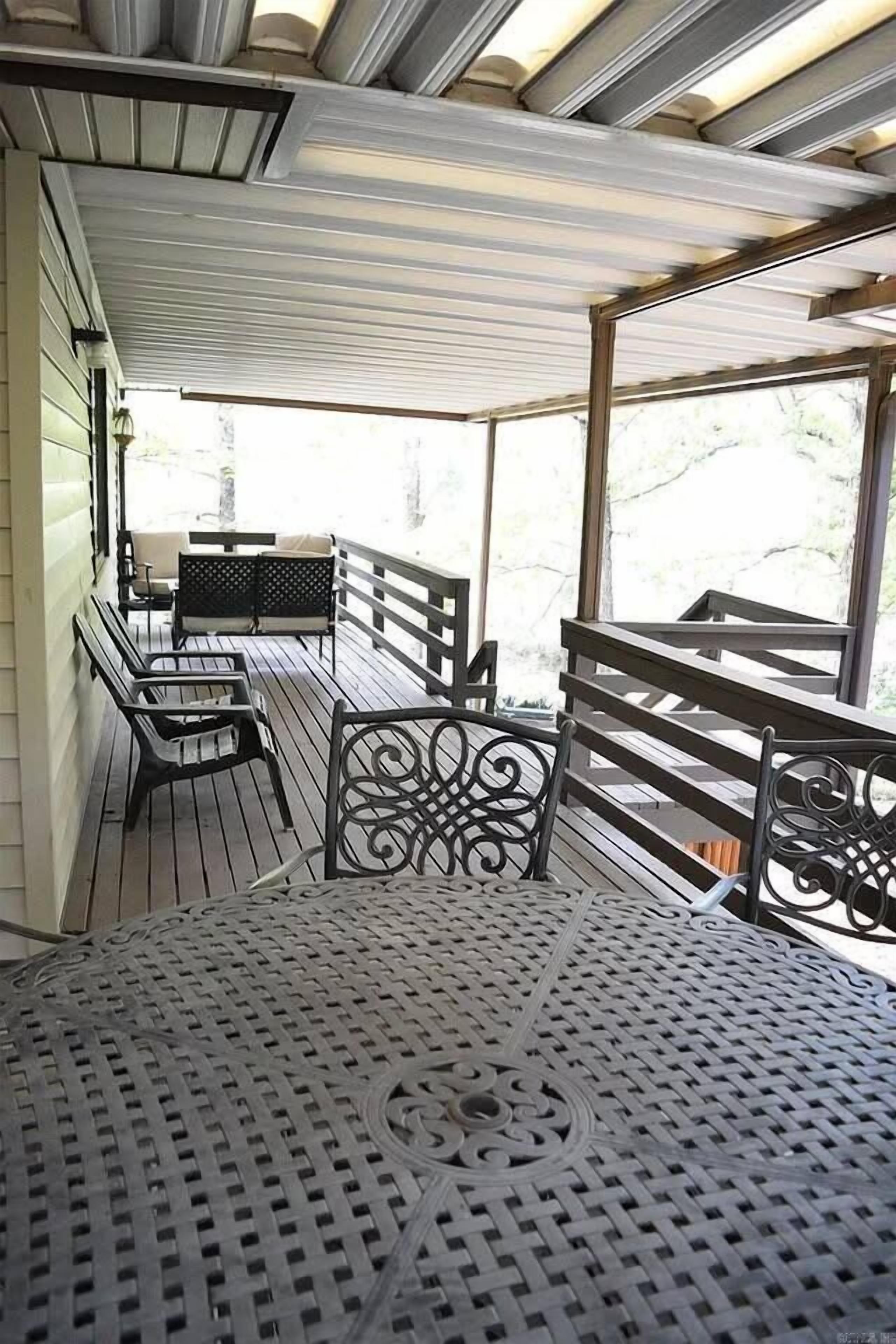 A covered outdoor seating area with metal chairs and a table, overlooking a natural landscape.
