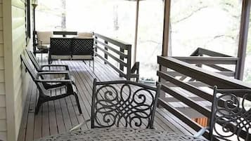 A covered outdoor seating area with metal chairs and a table, overlooking a natural landscape.