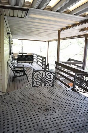 Un espacio de estar techado al aire libre con sillas de metal y una mesa, con vistas a un paisaje natural.