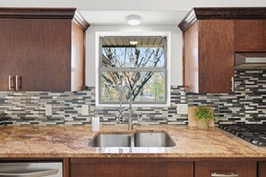 Una cocina con un lavamanos doble, una ventana y vistas a árboles.