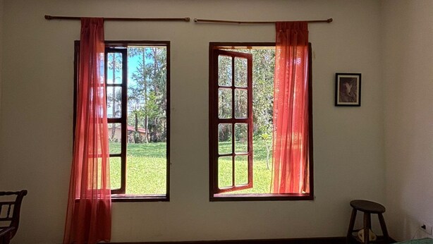 A room with a bed, two windows with curtains, a hanging light fixture, and a framed picture on the wall. - Cozy property for the whole family. 50km from São Paulo. (Caucaia do Alto)