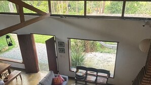 A spacious living area with a high ceiling, a sofa, a coffee table, and a view of the outdoors. - Cozy property for the whole family. 50km from São Paulo. (Caucaia do Alto)