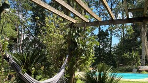 A hammock under a wooden pergola in a garden with a pool. - Cozy property for the whole family. 50km from São Paulo. (Caucaia do Alto)