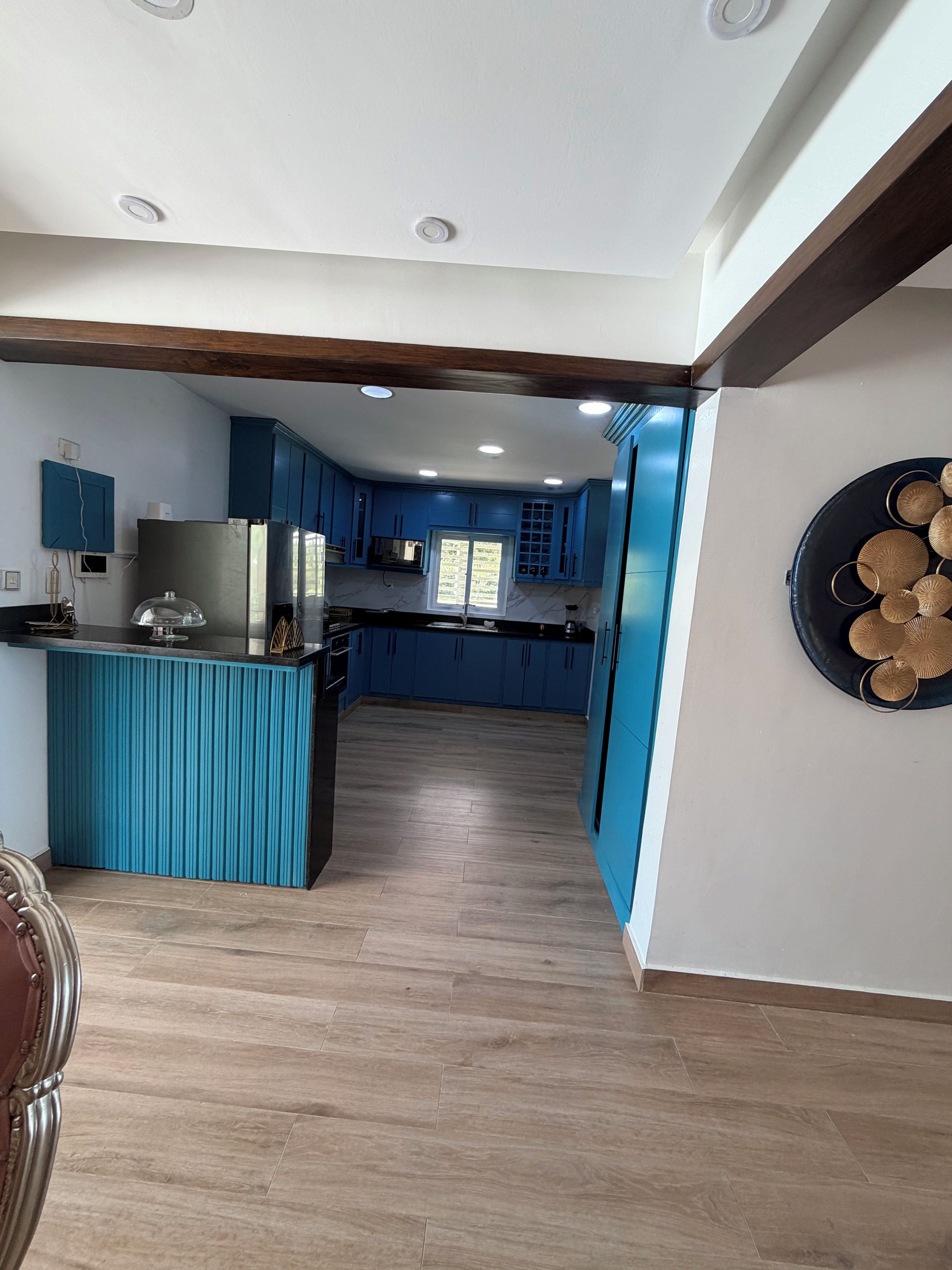 A modern kitchen with blue cabinets, a central island, and a decorative wall piece.