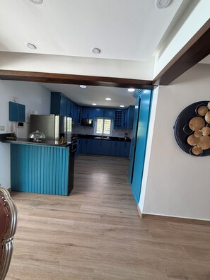 A modern kitchen with blue cabinets, a central island, and a decorative wall piece.
