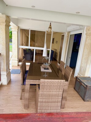 A dining area with a glass-top table, wicker chairs, and a chandelier.