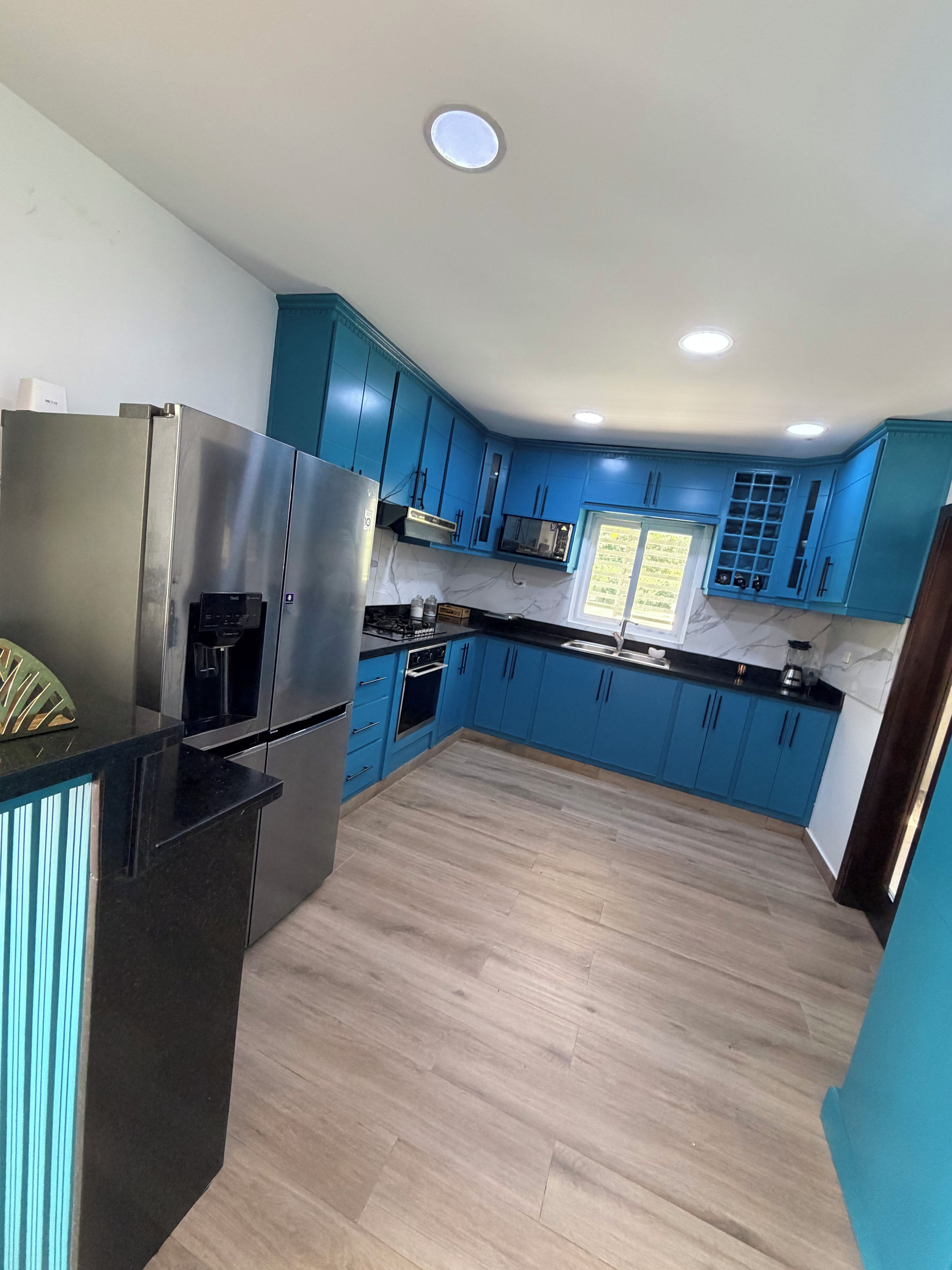 Eine moderne Küche mit blauen Schränken, Edelstahlgeräten und Holzboden.