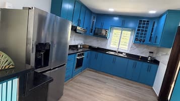 Eine moderne Küche mit blauen Schränken, Edelstahlgeräten und Holzboden.