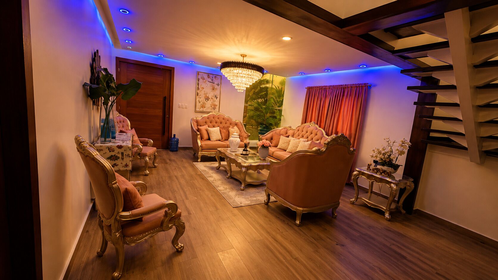 A spacious living room with a high ceiling, a chandelier, and a staircase.