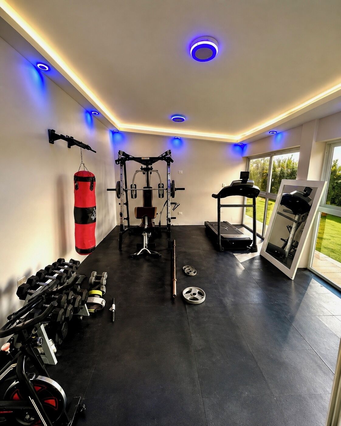 Ein Fitnessraum mit Trainingsgeräten, einem Boxsack und einem Laufband.