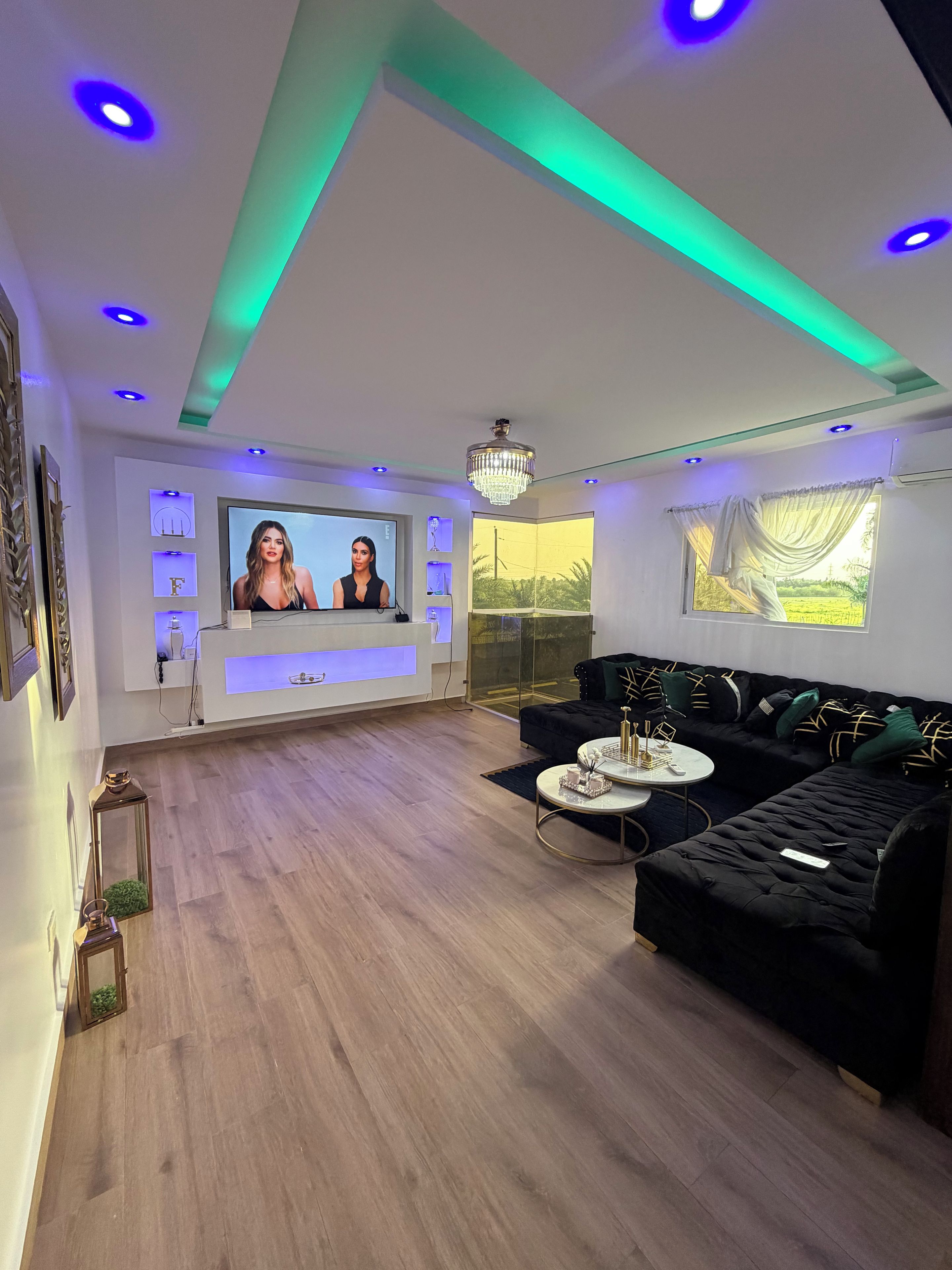 A modern living room with a black sofa, a round coffee table, and a television screen.