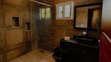 Ein modernes Badezimmer mit einer Glasdusche, Holzwänden, einem schwarzen Waschbecken und einem Spiegel.
