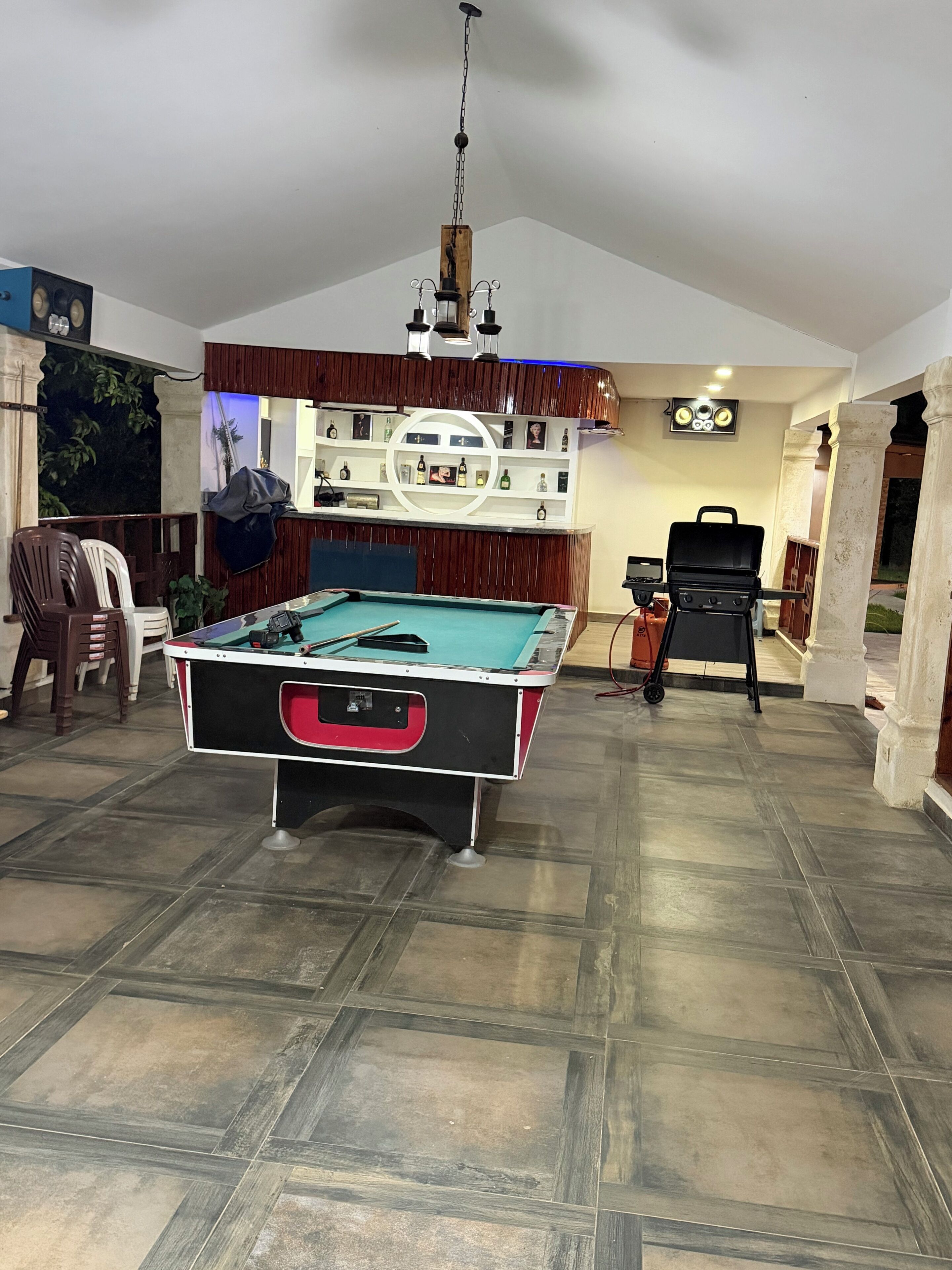 Una mesa de billar en una sala con barra de madera y estanterías llenas de botellas.