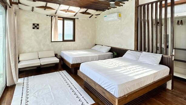 A room with two beds, a bench, and a window.