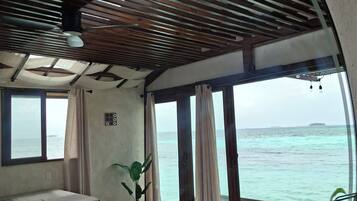 A room with a bed, a potted plant, and a view of the sea.