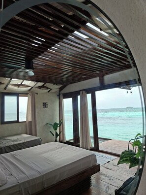 A room with a bed, a potted plant, and a view of the sea.