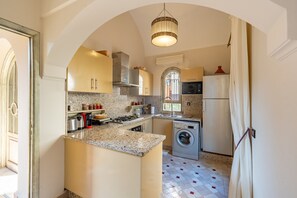 A compact kitchen with a central island, built-in appliances, and a window with decorative ironwork.
