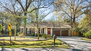 A residential street with a house featuring a garage, a driveway, and a landscaped front yard with a tree and a mailbox. - Delightful 3-bedroom house in charming Charleston (Charleston)