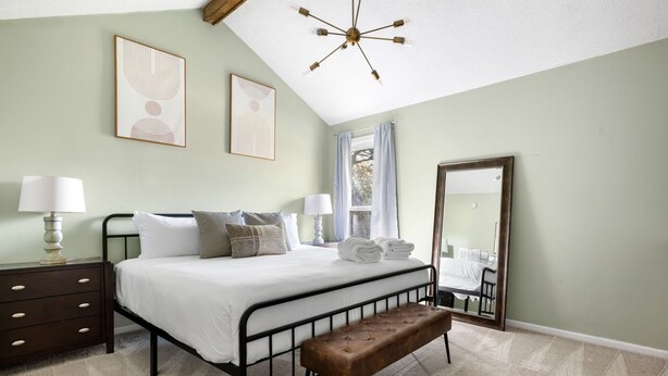 A bedroom with a bed, bedside tables, a bench, a mirror, and artwork on the walls. - Delightful 3-bedroom house in charming Charleston (Charleston)
