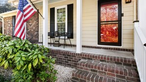 A house with a porch, a flag, and a door with a window. - Delightful 3-bedroom house in charming Charleston (Charleston)