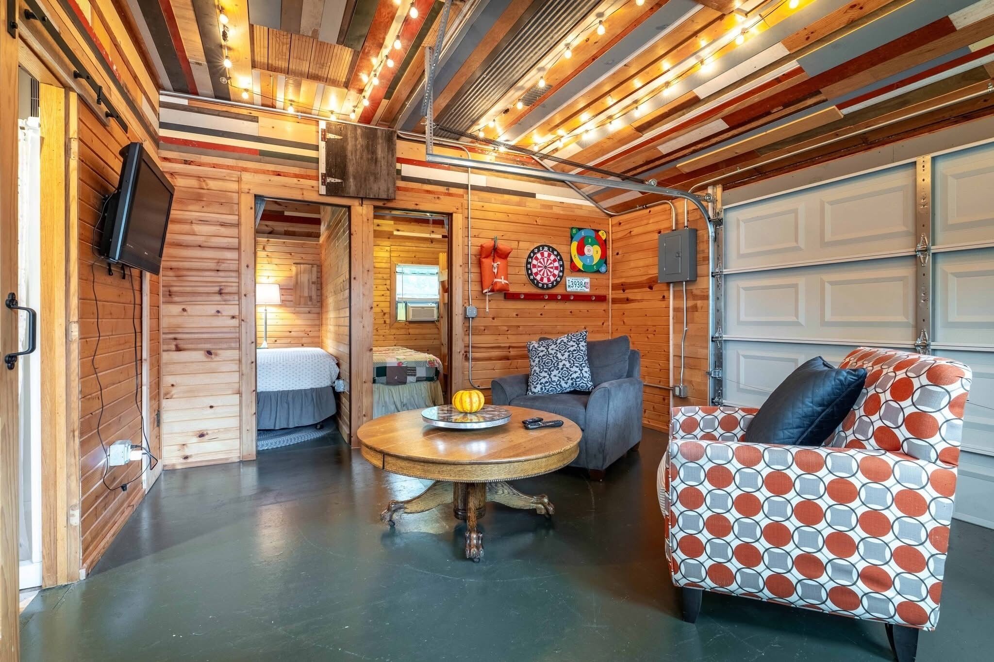 Un intérieur chaleureux avec une table ronde en bois, un canapé à motifs et un jeu de fléchettes accroché au mur.