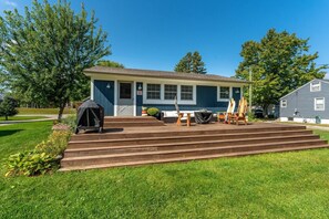 A house with a front porch, a covered grill, and a set of outdoor chairs.