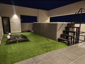 A modern outdoor area with artificial grass, a staircase, and a covered seating area. - Modern apartment in the city center, with everything you need in Naco, including a pool and an elevator (Santo Domingo)