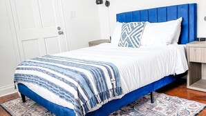 Ein Schlafzimmer mit Bett, Nachttisch, Lampe und Tür.