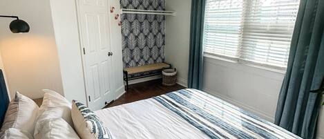 A bedroom with a bed, a ceiling fan, a window with curtains, and a patterned wall.