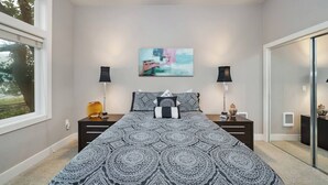 Ein Schlafzimmer mit einem großen Bett, zwei Nachttischen, einem Bild an der Wand und einem Fenster.