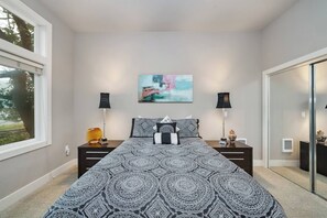 A bedroom with a large bed, two bedside tables, a painting on the wall, and a window. - Steps to Beach + Downtown, Oceanview | Full Duplex (Rockaway Beach)