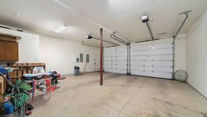 Eine Garage mit Betonboden, einer Holztür und einer Metalltür.
