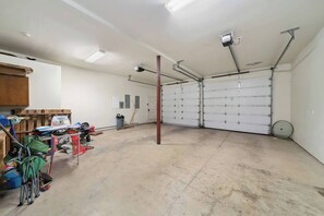 A garage with a concrete floor, a wooden door, and a metal door. - Steps to Beach + Downtown, Oceanview | Full Duplex (Rockaway Beach)