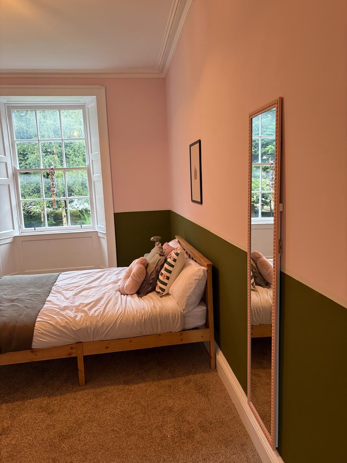 A bedroom with a bed, a window, and a mirror.