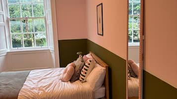 A bedroom with a bed, a window, and a mirror.