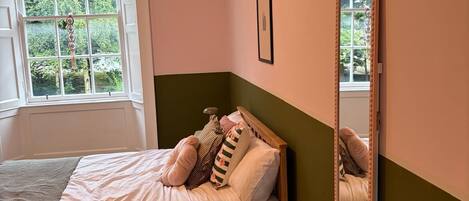 A bedroom with a bed, a window, and a mirror.
