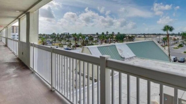 Ein Balkon mit Blick auf einen Swimmingpool und entfernte Gebäude.