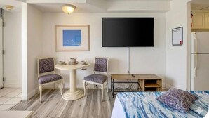 Ein Hotelzimmer mit Bett, Fernseher, kleinem Tisch mit Stühlen und einem gerahmten Bild an der Wand.
