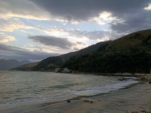 Paesaggio costiero con spiaggia, onde e una montagna sullo sfondo.