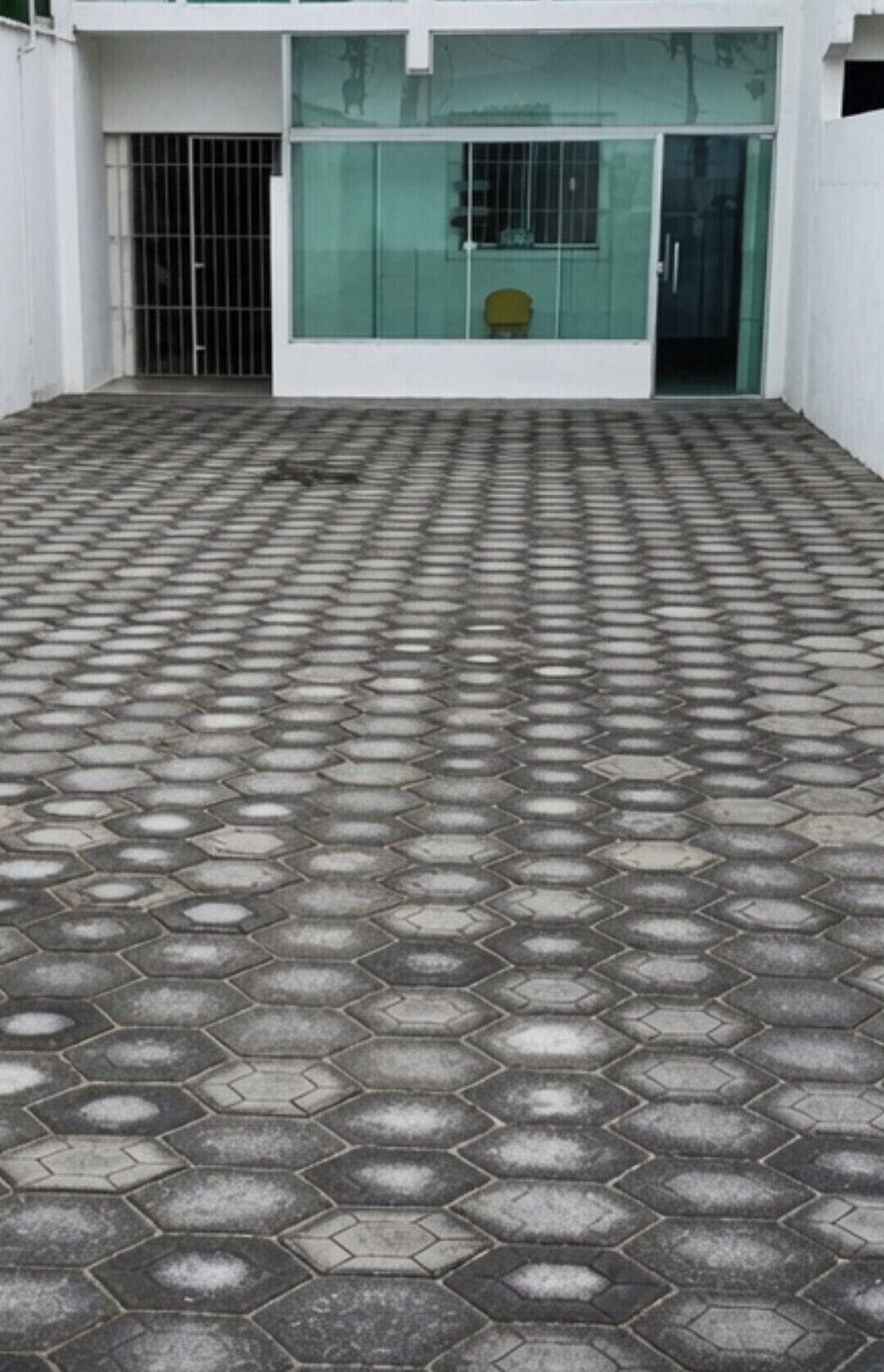 A hexagonal patterned floor leading to a building entrance with a glass door and a metal gate.