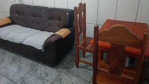 Um quarto com um sofá marrom escuro, uma cadeira de madeira e uma pequena mesa de madeira.